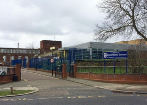 School with red brick and fencing and blue sign