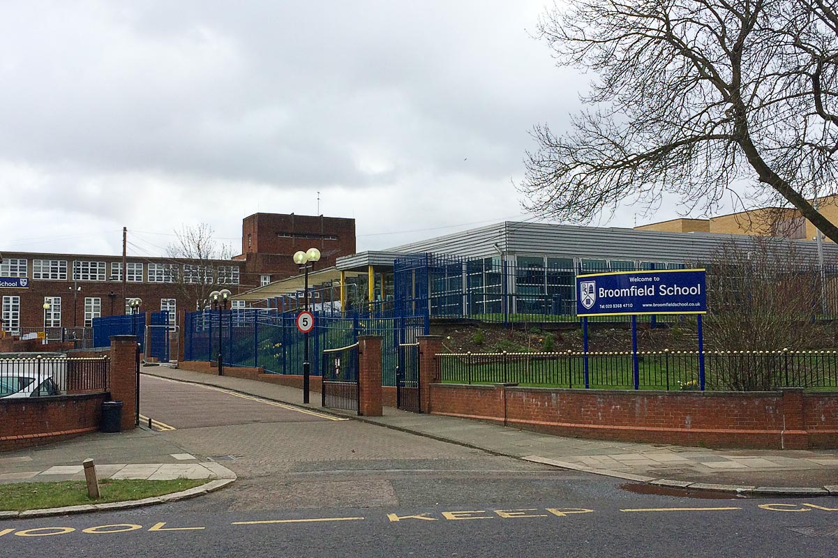 School with red brick and fencing and blue sign