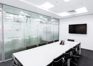 office building with white desk and itv on the wall, glass doors and walls