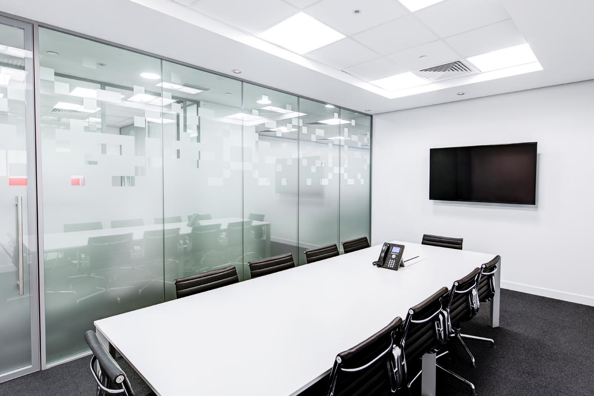 office building with white desk and itv on the wall, glass doors and walls