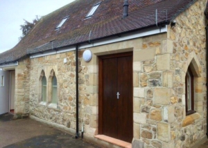 yellow stone brick house with wooden front door and pointed windows